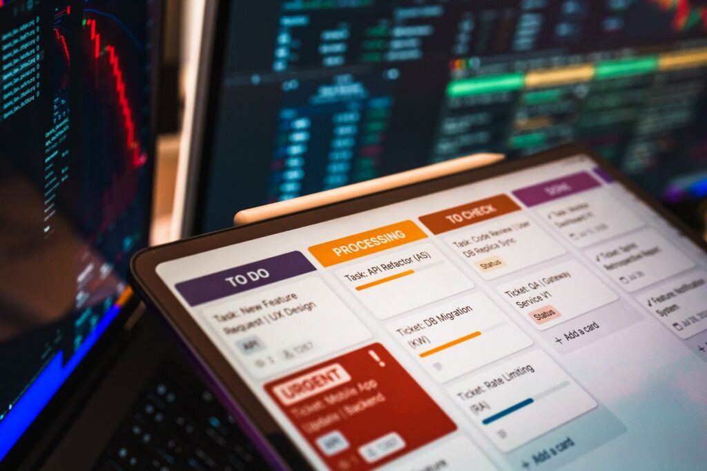 Laptop met dashboard en takenbord, schermen met data op de achtergrond